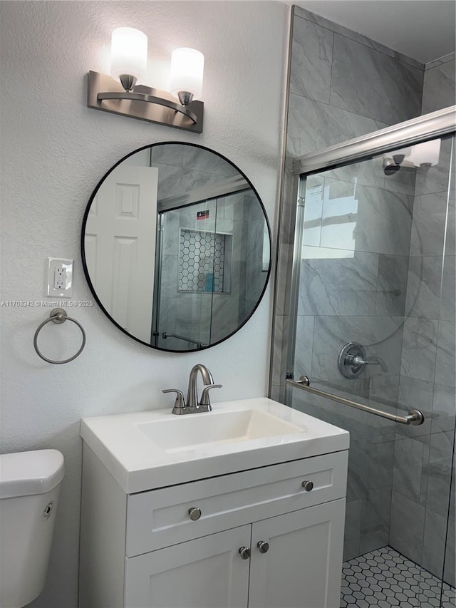 bathroom with vanity, a shower with shower door, and toilet