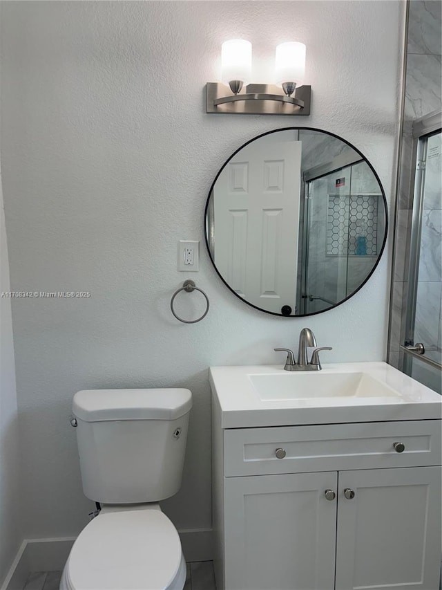 bathroom with vanity, toilet, and a shower with door