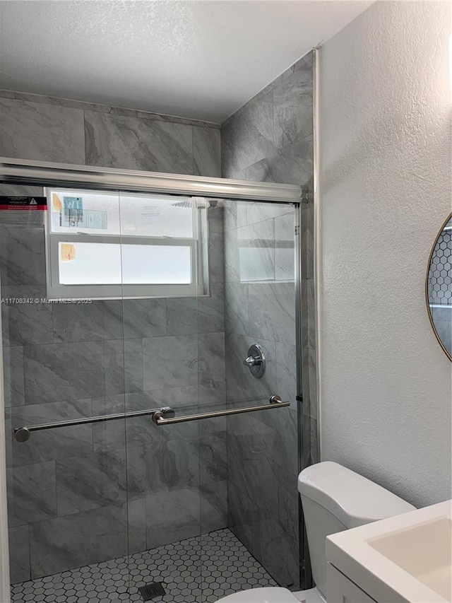 bathroom featuring vanity, a shower with shower door, and toilet