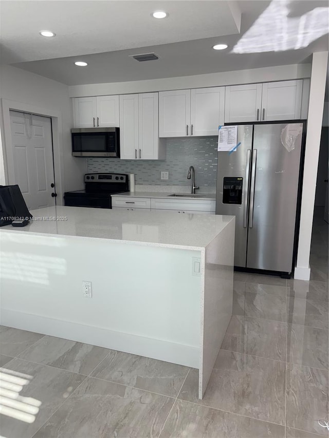 kitchen with white cabinetry, sink, a center island, stainless steel appliances, and decorative backsplash