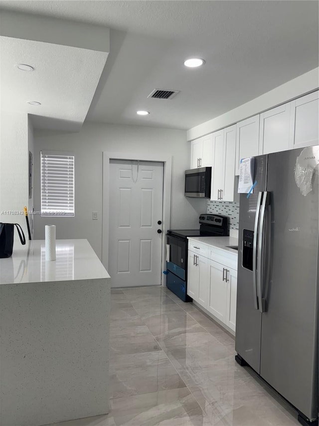 kitchen featuring backsplash, stainless steel appliances, and white cabinetry