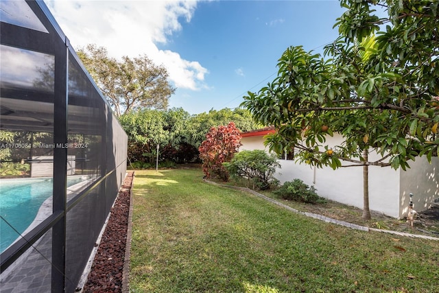 view of yard with a fenced in pool and glass enclosure