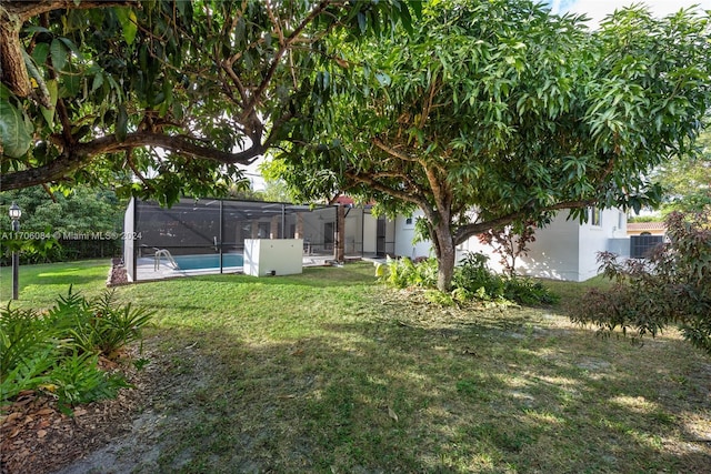 view of yard featuring a fenced in pool and glass enclosure