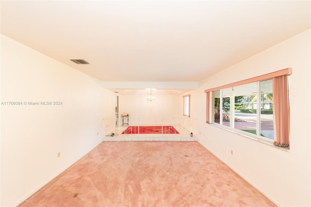 empty room featuring carpet floors and a chandelier