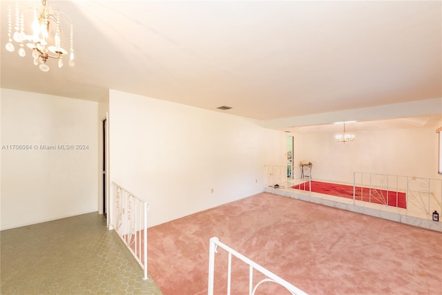 carpeted empty room featuring an inviting chandelier