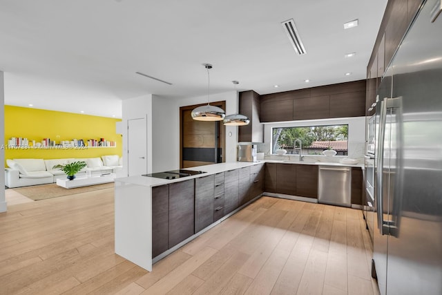 kitchen with sink, hanging light fixtures, light hardwood / wood-style flooring, dark brown cabinets, and stainless steel appliances