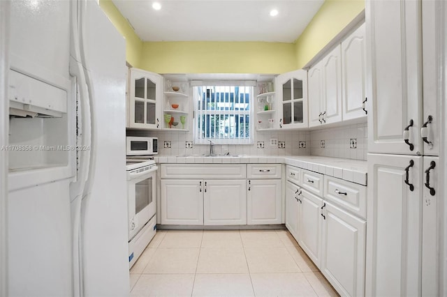 kitchen featuring white appliances, white cabinetry, tile counters, and sink