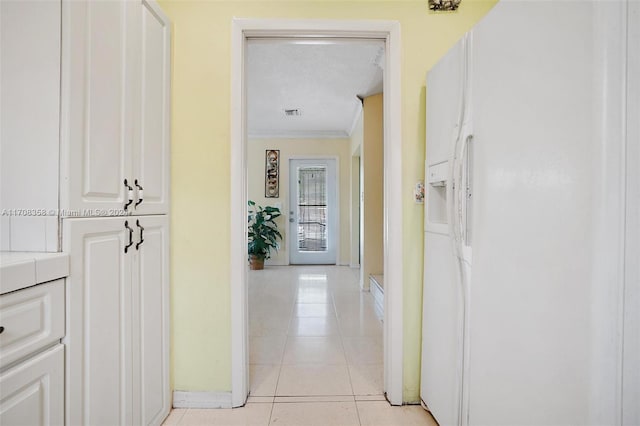 corridor with a textured ceiling, crown molding, and light tile patterned flooring