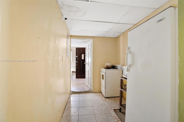 hallway with a drop ceiling, washer / dryer, and light tile patterned floors