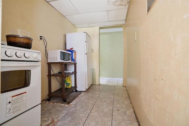 corridor with a drop ceiling and light tile patterned floors