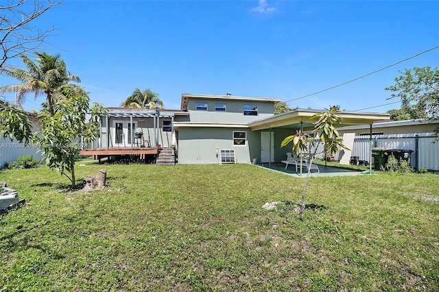 rear view of house with a wooden deck, a patio area, and a lawn