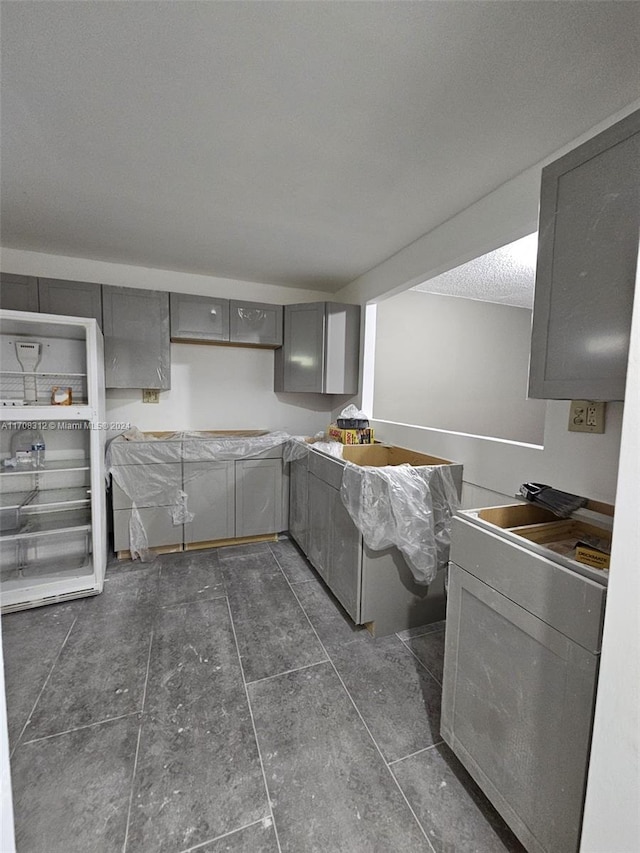 kitchen featuring a textured ceiling, gray cabinets, and dark tile patterned floors