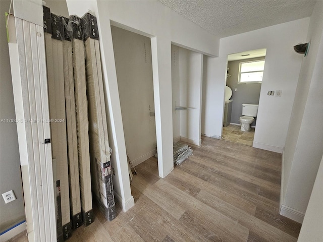 interior space featuring toilet, wood-type flooring, and a textured ceiling