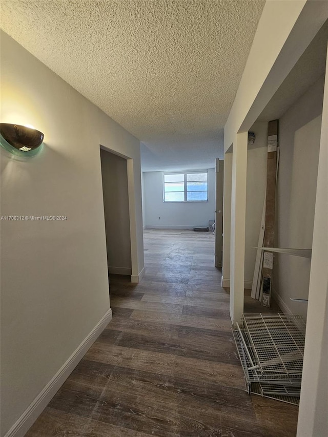 corridor featuring a textured ceiling and dark hardwood / wood-style flooring