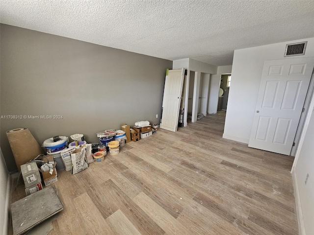 unfurnished room featuring light hardwood / wood-style flooring and a textured ceiling