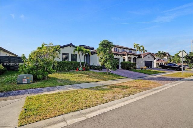 mediterranean / spanish-style house featuring decorative driveway, stucco siding, a garage, a residential view, and a front lawn