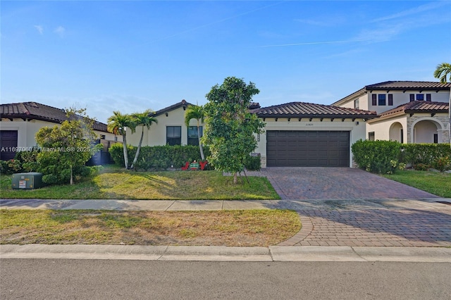 mediterranean / spanish-style home featuring a tiled roof, decorative driveway, an attached garage, and stucco siding