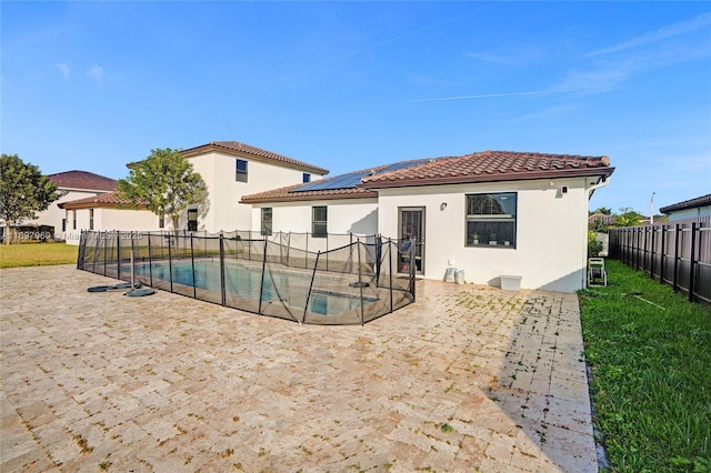 rear view of house featuring a tile roof, a fenced in pool, a fenced backyard, solar panels, and stucco siding