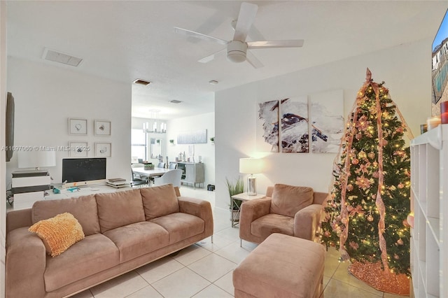 living area featuring light tile patterned flooring, visible vents, and ceiling fan with notable chandelier