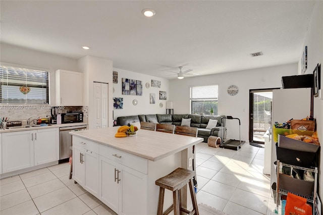 kitchen with visible vents, white cabinetry, a sink, dishwasher, and backsplash