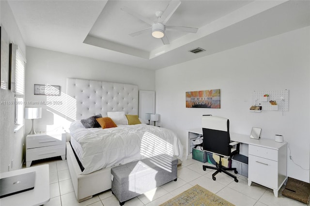 bedroom featuring visible vents, a raised ceiling, a ceiling fan, and light tile patterned floors