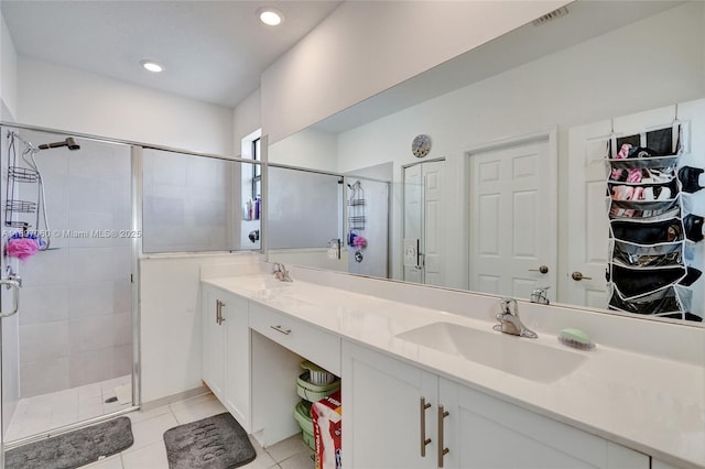 bathroom featuring double vanity, tile patterned flooring, a stall shower, and a sink