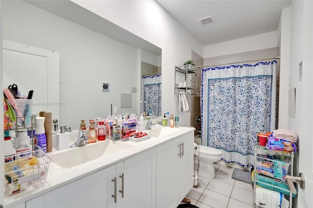 bathroom featuring tile patterned flooring, visible vents, toilet, double vanity, and a sink