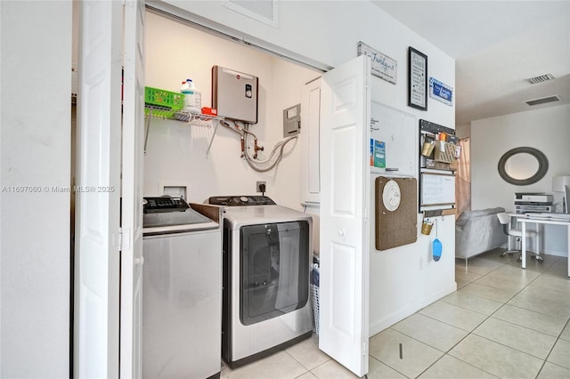 laundry area with light tile patterned floors, laundry area, washing machine and dryer, and visible vents