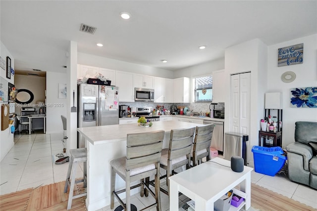 kitchen with visible vents, light countertops, appliances with stainless steel finishes, white cabinetry, and tasteful backsplash