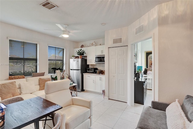 living room with light tile patterned floors, visible vents, and ceiling fan