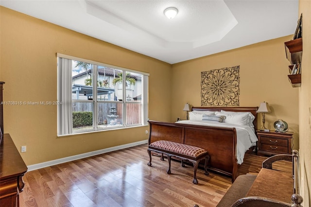 bedroom featuring light wood-type flooring and a raised ceiling