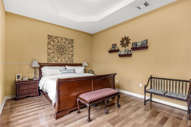 bedroom featuring a tray ceiling and light wood-type flooring