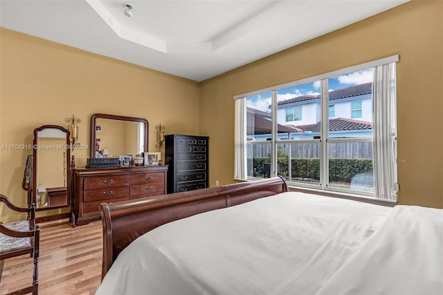 bedroom featuring a tray ceiling and light hardwood / wood-style flooring