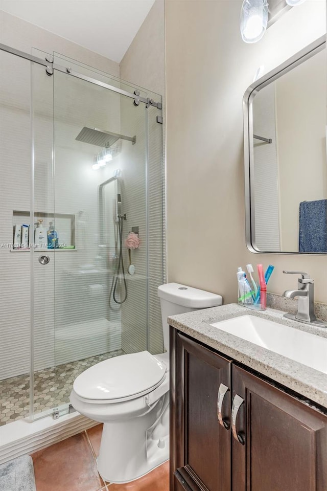 bathroom with tile patterned floors, a shower with door, vanity, and toilet