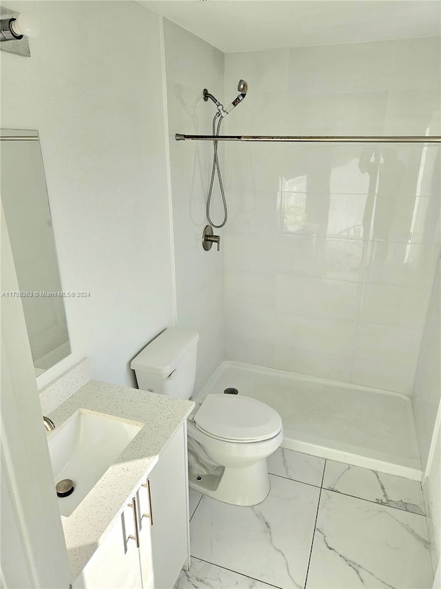 bathroom with tiled shower, vanity, and toilet