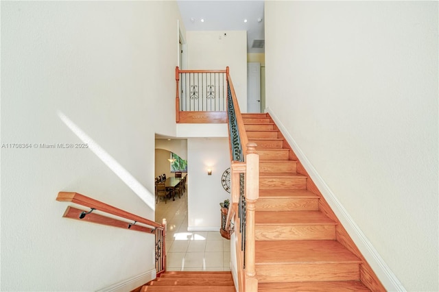 stairway with tile patterned flooring and a towering ceiling