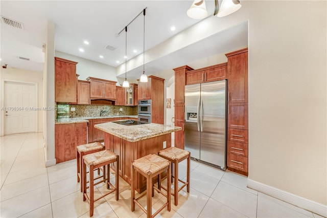 2913 SW 13th St, Miami, FL 33145 - kitchen with stainless steel appliances, brown cabinetry, a center island, light tile patterned floors, and backsplash