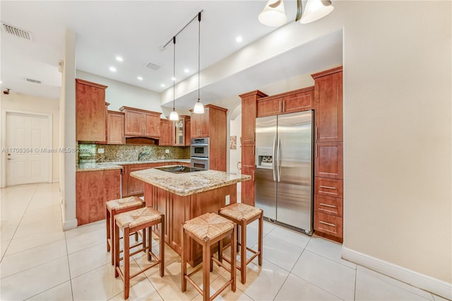 kitchen with a breakfast bar, appliances with stainless steel finishes, decorative light fixtures, a kitchen island, and light stone counters