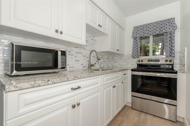 kitchen featuring sink, stainless steel appliances, light stone counters, light hardwood / wood-style floors, and white cabinets