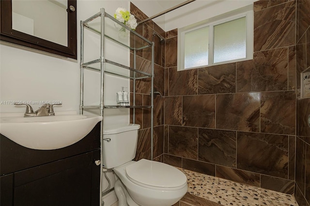 bathroom with vanity, toilet, and a tile shower