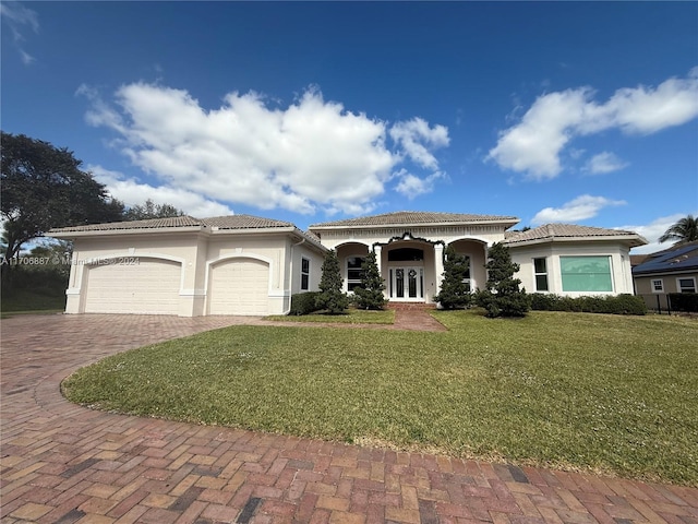 mediterranean / spanish house with french doors, a front yard, and a garage