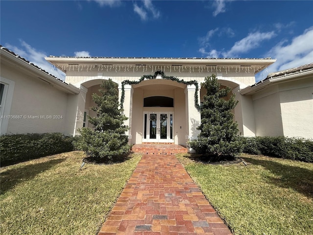 doorway to property featuring a yard and french doors