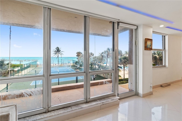 doorway to outside featuring light tile patterned floors, floor to ceiling windows, and a water view