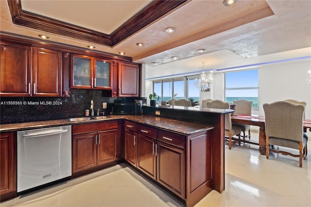 kitchen with a raised ceiling, hanging light fixtures, stainless steel dishwasher, and sink