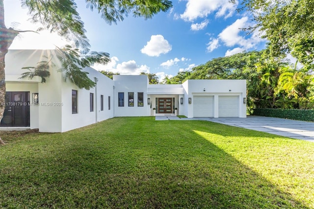 view of front of home with french doors, stucco siding, an attached garage, a front yard, and driveway