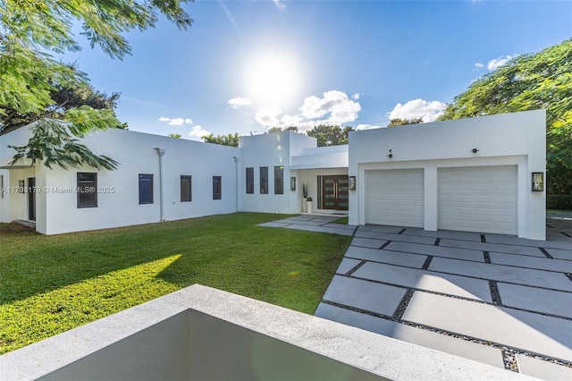 view of front of house featuring driveway, an attached garage, french doors, a front lawn, and stucco siding