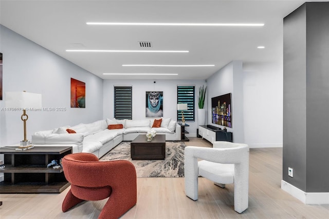 living area featuring visible vents, baseboards, and wood finished floors