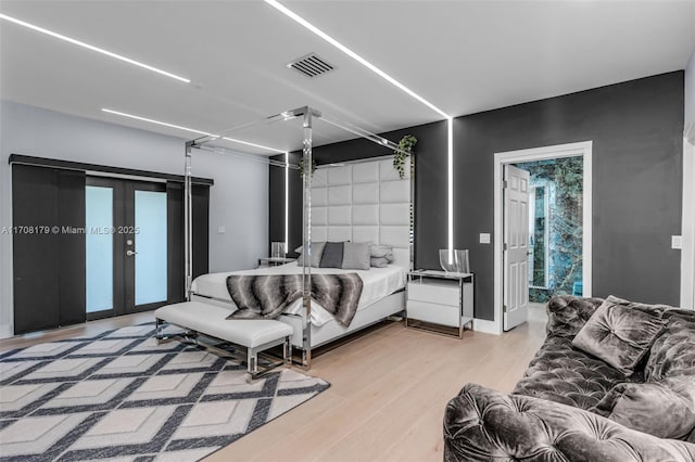 bedroom featuring access to exterior, french doors, visible vents, and light wood-style flooring