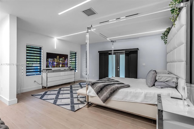 bedroom with visible vents, baseboards, and wood finished floors