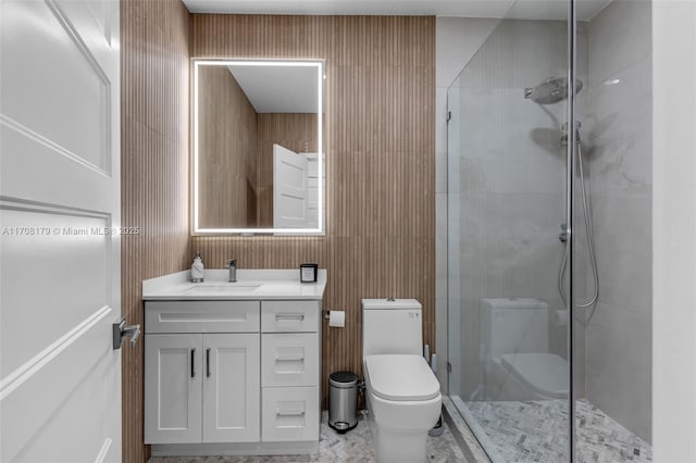 bathroom featuring marble finish floor, tiled shower, vanity, and toilet